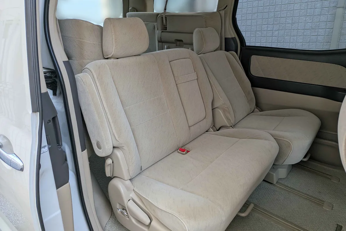 Второй ряд Toyota Alphard: бежевый тканевый диван у открытой сдвижной двери